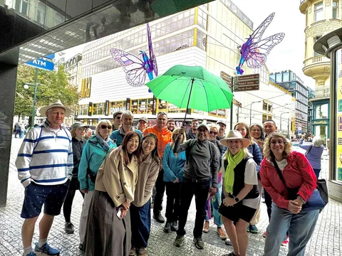 New Town tour guests with a green umbrella beneath colourful butterfly sculptures.