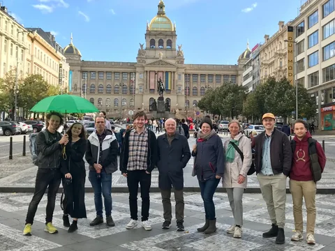 Tour group with a green umbrella on Wenceslas Square, with the National Museum in the background.