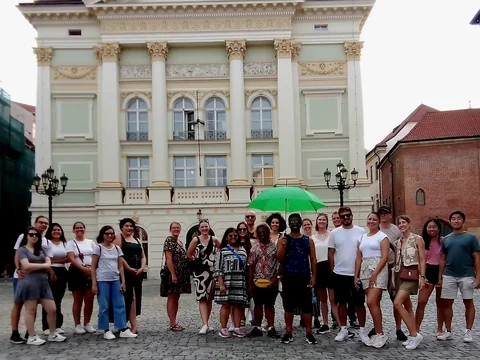 Travellers with a green tour umbrella outside the Estates Theatre in Prague Old Town.