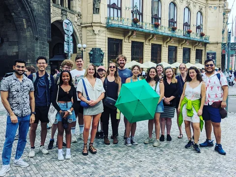 Old Town tour guests gathered with a green umbrella beside the Powder Gate.