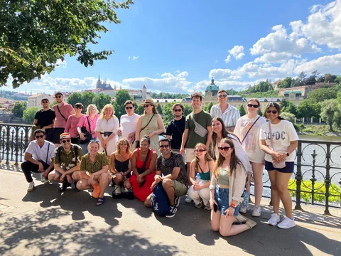 Travellers on the Old Town tour beside the Vltava, with Prague Castle across the river.